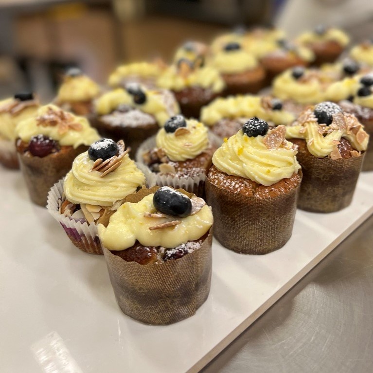 Lemon and Blueberry Vegan Muffins, topped with almonds and blueberries on a white serving board